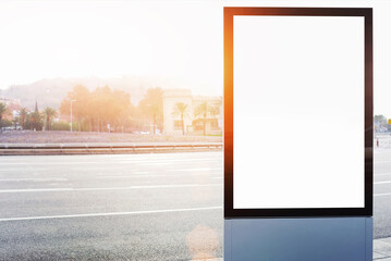 Blank billboard with copy space for your text message or content, outdoors advertising mock up, public information board on city road, flare sun light. Empty Lightbox on urban setting sidelines