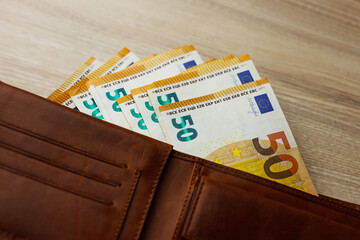 Wallet stuffed with Euro banknotes on the wooden backround