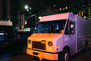 White van of delivery shipping service parked on road in downtown at night. postal truck body of logistic company on city street, derived van for relocation and transporting stuff