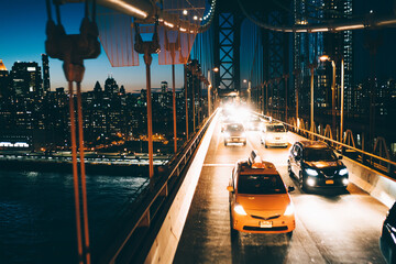 Yellow cabs and cars moving by Manhattan bridge to other side of megalopolis with shining city...
