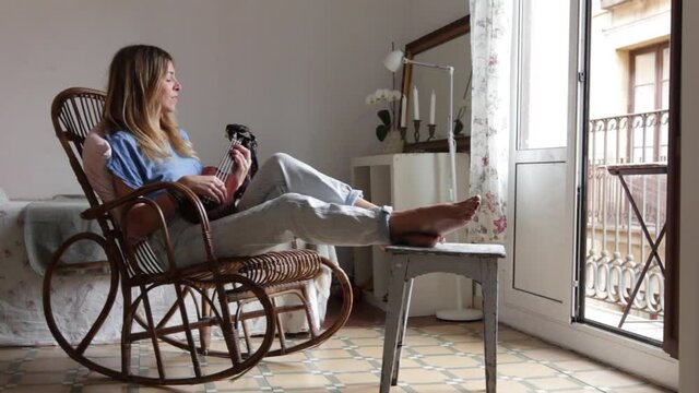 Woman at home sitting on an old chair ply ukelele 