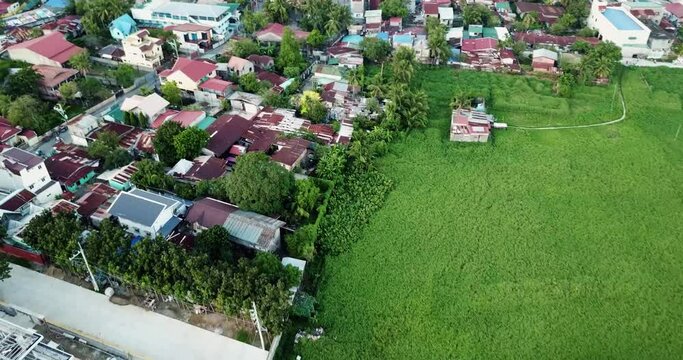 Graded aerial flyover dolly in birds eye view shot of houses, neighbourhood, streets, roads and traffic of cars, bikes and tricycles of a village, town, regional city in philippines south east asia