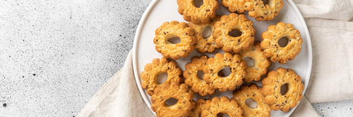 Shortbread in a large white ceramic plate on the light gray kitchen table. There are a lot of cookies in the plate. Homemade delicious pastries. Top view with a space for text. Banner	