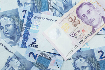 A close up image of a two dollar bill from Singapore close up in macro with Brazilian two reais bank notes