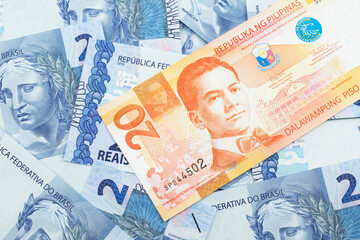 An orange twenty piso bank note from the Philippines with Brazilian two reais bank notes close up in macro