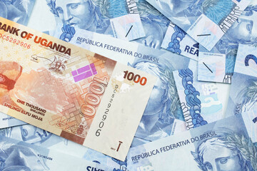 A close up image of a colorful Ugandan shilling bank note with Brazilian two reais bank notes in macro