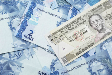A close up image of a one Ethiopian birr bank note on a background of Brazilian two reais bank notes
