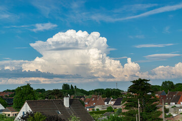 Unusual arrangement of large clouds in the blue sky above the city.