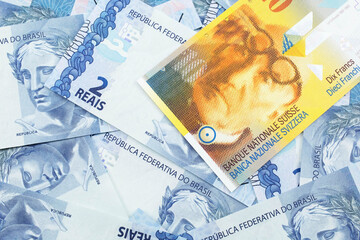 A yellow, ten Swiss franc note from Switzerland close up in macro with Brazilian two reais bank notes