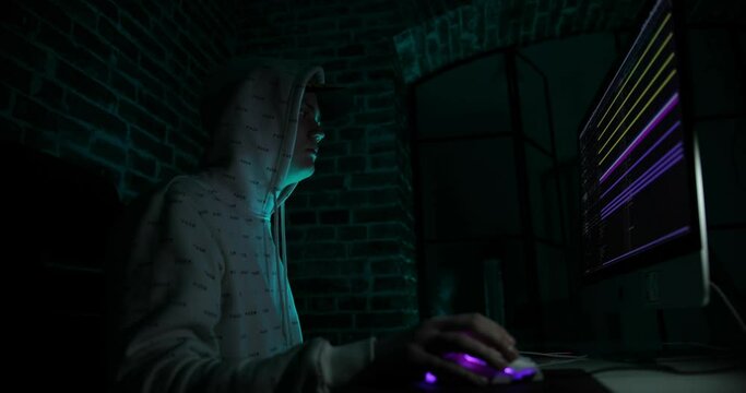 Hacker in the hood working with computer typing text in dark room. Image with effect. newest computer technologies.