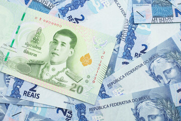 Naklejka premium A close up image of a green, twenty baht note from Thailand with Brazilian two reais bank notes in macro