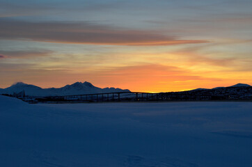 vibrant colourful dawn sky sunset over mountain in winter with tromsoe city island and bridge