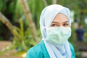 Muslim woman with hijab is wearing face mask outdoors