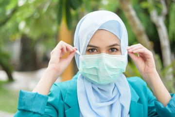 Muslim woman with hijab is wearing face mask outdoors
