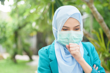 Muslim woman with hijab is wearing face mask outdoors