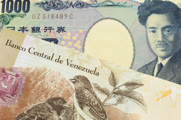 A macro image of a Japanese thousand yen note paired up with a colorful one hundred Bolivar bank note from Venezeula.  Shot close up in macro.