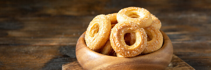 Sprinkle the puff pastry with sugar in a wooden bowl on a wooden table. Sprinkle the cookies with sugar. Sweet pastries. Banner