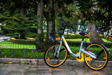 Fototapeta premium Yellow rental public bike parked at the Paseo del Prado on a rainy day in Madrid