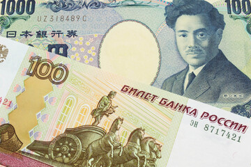 A macro image of a Japanese thousand yen note paired up with a Russian one hundred ruble note.  Shot close up in macro.