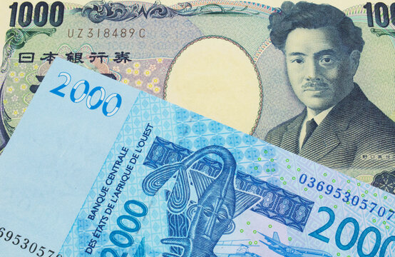 A macro image of a Japanese thousand yen note paired up with a blue, two thousand West African franc bank note.  Shot close up in macro.