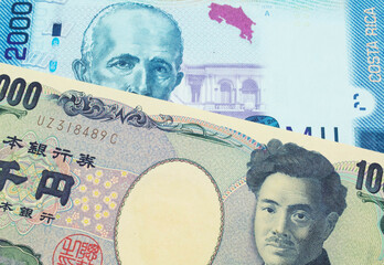 A macro image of a Japanese thousand yen note paired up with a colorful two thousand colones bank note from Costa Rica.  Shot close up in macro.