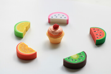 Fruit slices around a toy cake on a white background