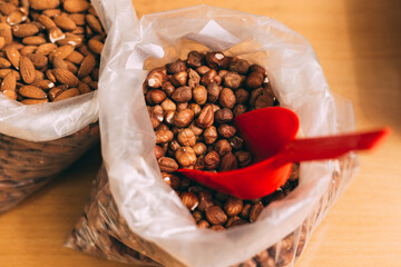 Heap of  hazelnuts and almonds in transaprent nylon bag on wooden shop counter. Nuts in bulk. Top view.