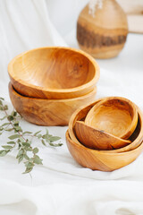 Wooden bowls on a white piece of clothing in a bright room. Close up.