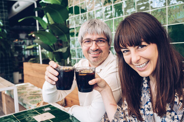 Smiling friends celebrating in a colorful restaurant toasting while looking at the camera
