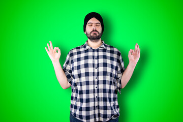 Closeup portrait young bearded man praying hands clasped hoping for best asking for forgiveness or miracle isolated green wall background. Human emotion facial expression feeling