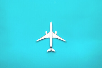 Flight plane travel concept. White toy airplane, aircraft on bright blue. Air sky fly background.