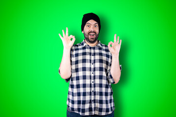 Naklejka premium Portrait of a cheerful young man showing okay and victory gesture isolated on the chroma background