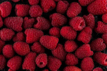 juicy raspberries on a black background, dry and with water drops