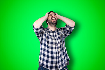 Portrait of a puzzled bearded man holding hands on his head isolated over chroma background