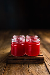 Red colored alcoholic shooters, or shot drinks on wooden table, with copy space