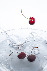 Three fresh red cherries dropped into water with splash
