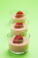 Strawberry panna cotta in glass cup and green background