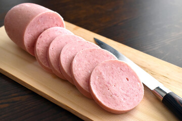 Greek Parizaki pork stick slices on the cutting board with a knife on the right side.  Selective focus.  Copy space is on the right side. 