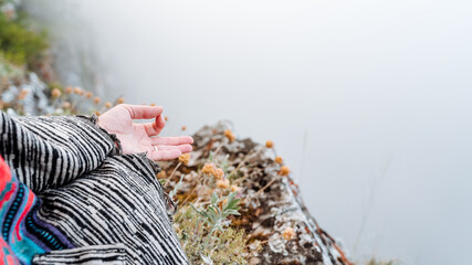 fingers folded in mudra against the background of mountains and fog, a state of peace and tranquility, Zen, yoga in nature