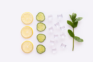 Creative summer drink composition. With lemon slices, mint leaves , cucumber and ice cubes. Minimal flat lay lemonade drink concept. On white background