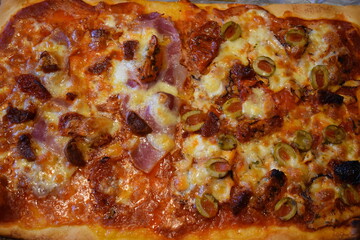 Piping hot hand baked at home Italian style non vegetarian pizza. Shop bought dough containing gluten with red ripe tomato and basil sauce Baby mozarella salami smoked bacon octopus carpaccio toppings