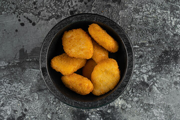 A portion of delicious and crispy chicken nuggets on grey background. A popular fast food made from chicken meat