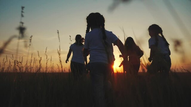 happy family children kids together run in the park at sunset silhouette. people in the park concept mom dad daughter and son joyful run. parents and little baby child fun summer vacation running