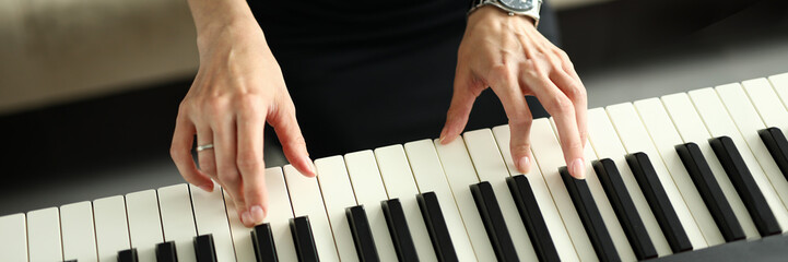 Female hands playing electric piano at home