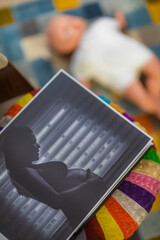photo album of pregnant woman with doll lying on colorful carpet