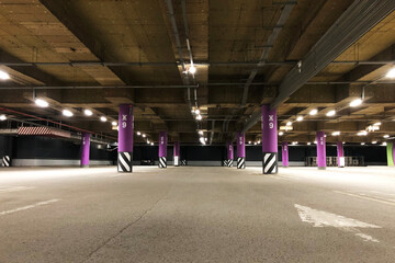 empty underground parking lot with colorful columns and light on ceiling  on basement of shopping mall. No cars, no people due to non-working store hours.