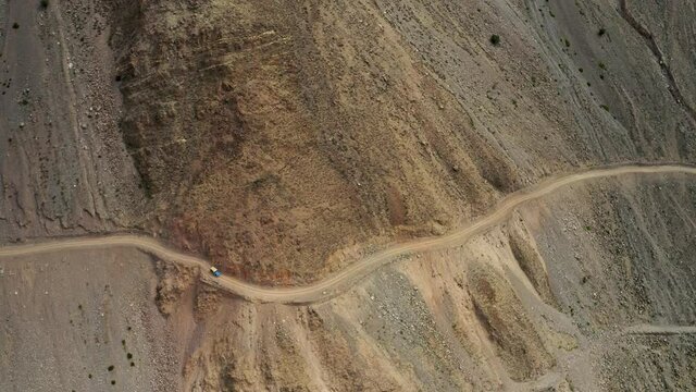 Aerial view of the curvy mountain road on a hillside of a large mountain