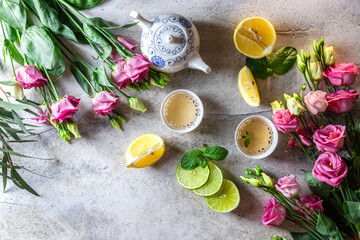Tea set, lemon, mint and flowers on a light concrete background. View from above. Tea party concept.