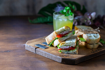 Ciabatta sandwich with turkey, lettuce, tomatoes, cheese on a wooden board.