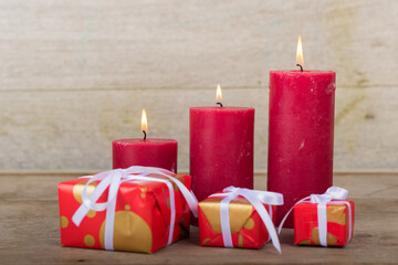 Christmas holidays composition with decorations (red candles and presents) on white wooden board background with copy space for your text.